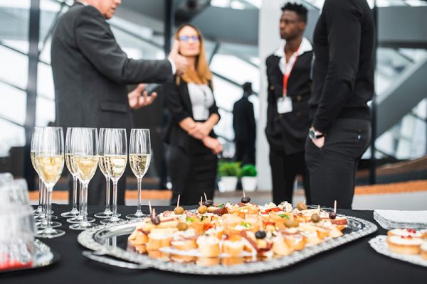 A group of four people conversing near a table with hors d'oeuvres and glasses of champagne at a formal event.