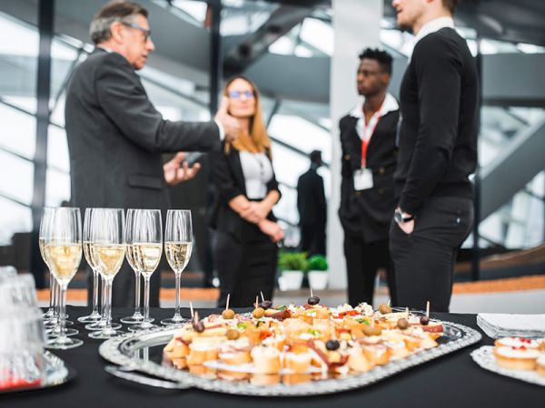 A group of four people conversing near a table with hors d'oeuvres and glasses of champagne at a formal event.