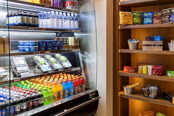 The image shows a refrigerated display with drinks, yogurt, and pre-packaged food, alongside shelves stocked with snacks and other items.