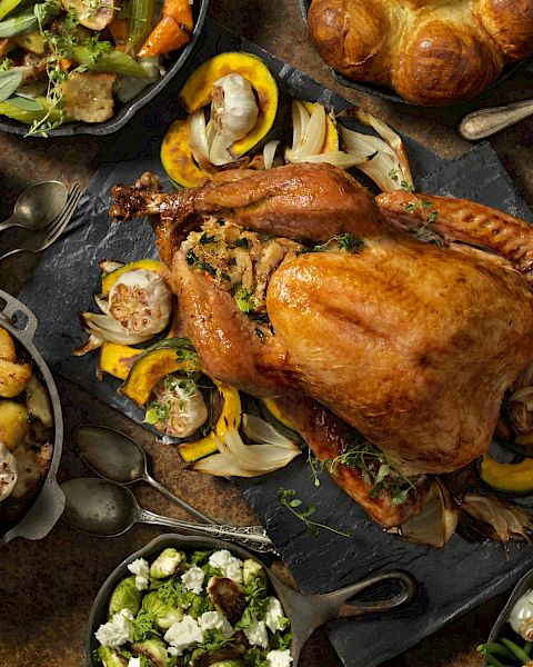 The image shows a Thanksgiving meal with roast turkey, potatoes, vegetables, salad, cranberry sauce, and bread on a table.