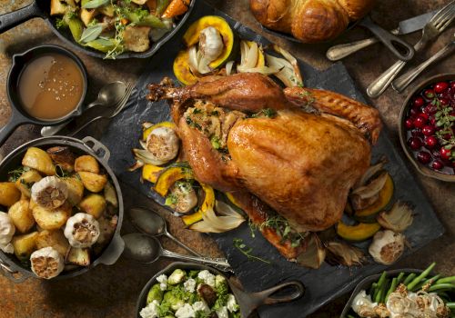 The image shows a Thanksgiving meal with roast turkey, potatoes, vegetables, salad, cranberry sauce, and bread on a table.