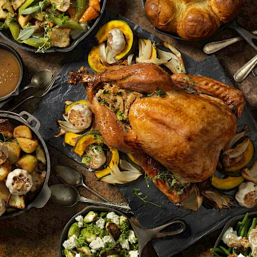 The image shows a Thanksgiving meal with roast turkey, potatoes, vegetables, salad, cranberry sauce, and bread on a table.