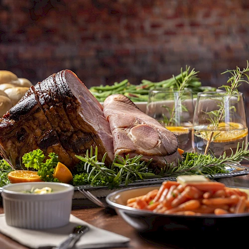 A bountiful spread featuring roast meat, rolls, vegetables, and garnishes with drinks. A festive and hearty meal arrangement.