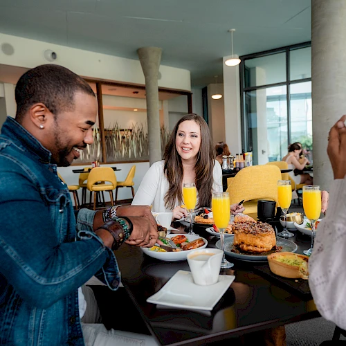 People are enjoying a meal at a restaurant, with plates of food, orange juice, and coffee on the table.