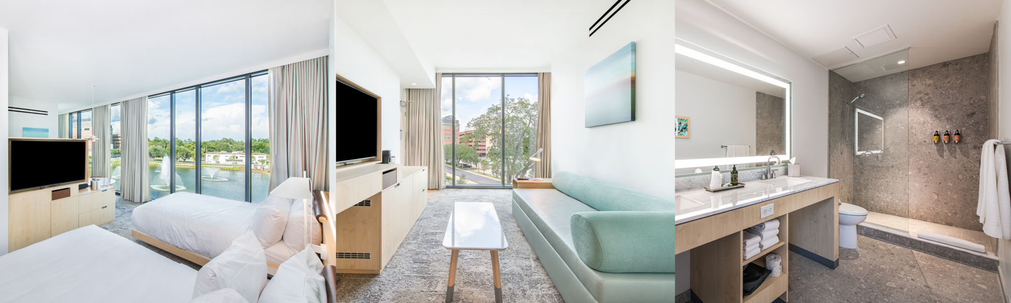 The image shows a modern hotel room with a bed, TV, large windows, a lounge area, and a well-lit bathroom with a shower and towels.